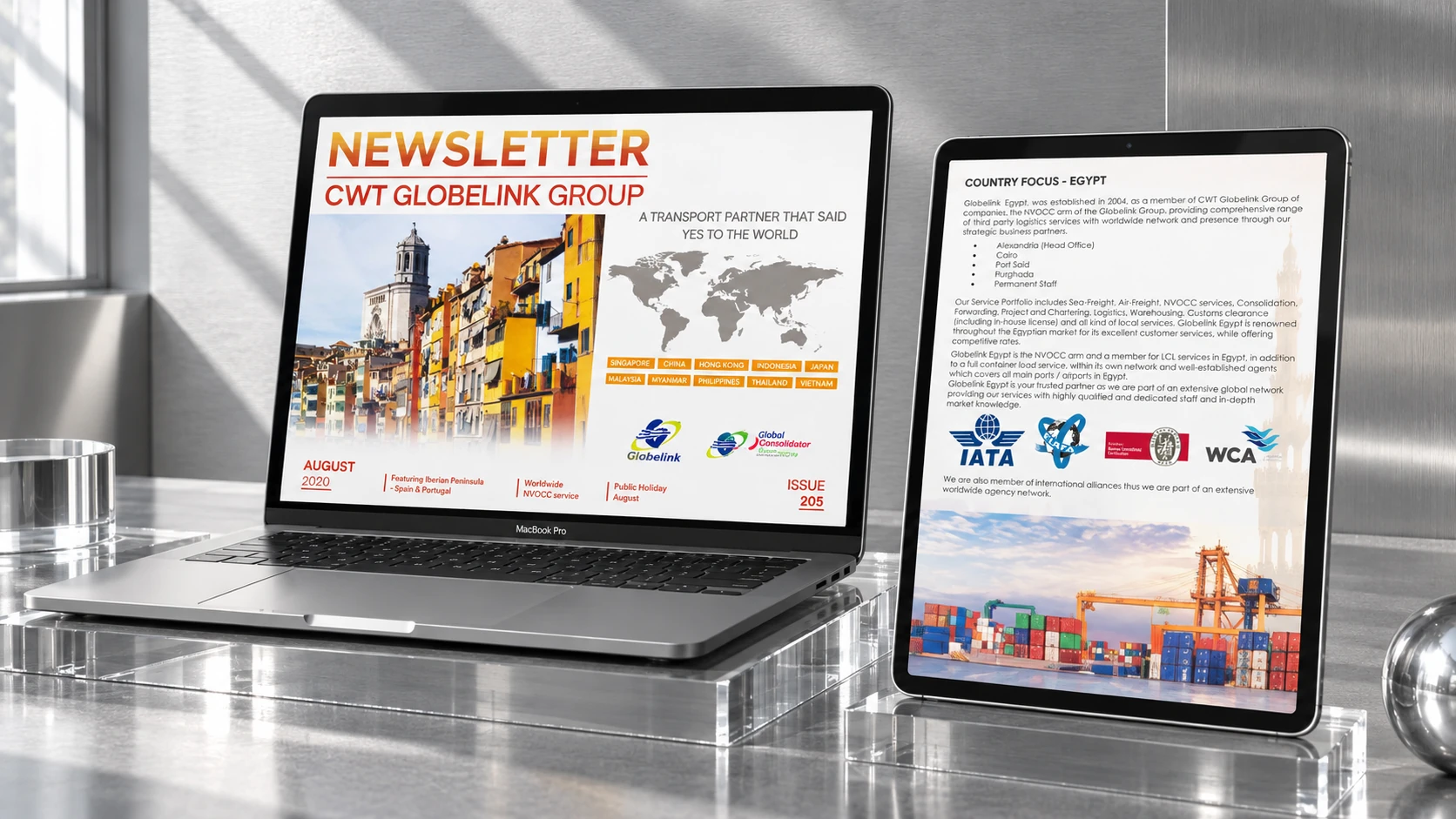 A laptop and tablet displaying CWT Globelink email newsletter content in a sunlit metallic setting.