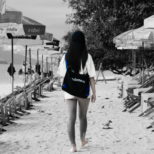 Gate branded bag and cap on a beach, with small blue accents.
