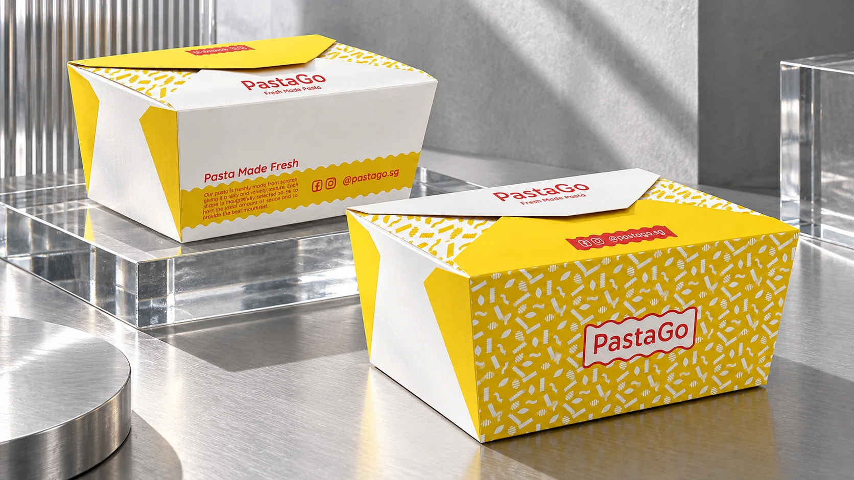 Two yellow and white PastaGo takeaway cartons on glass and brushed-metal display plinths.